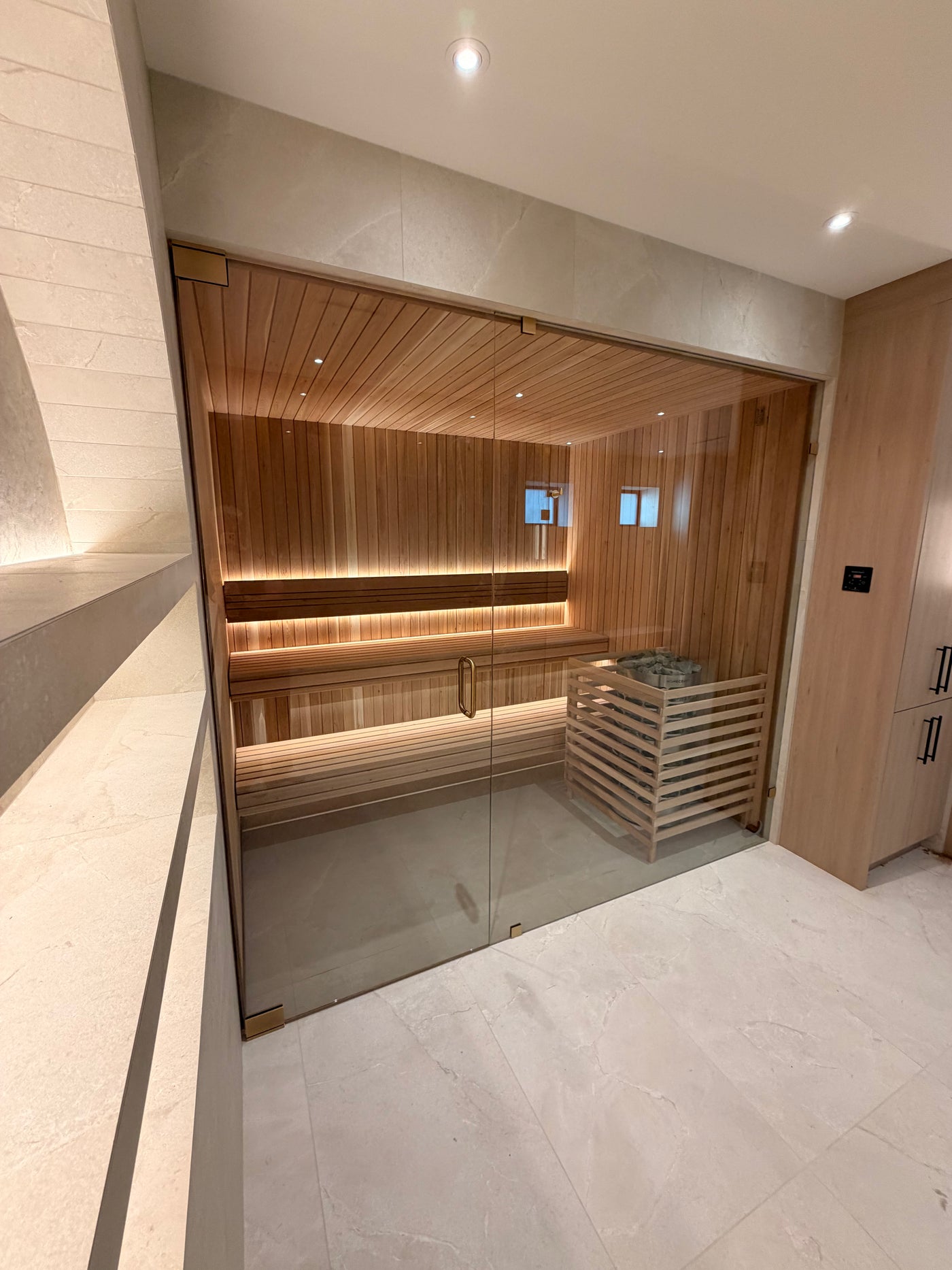 Clear cedar sauna behind a custom glass front, built by Inland
