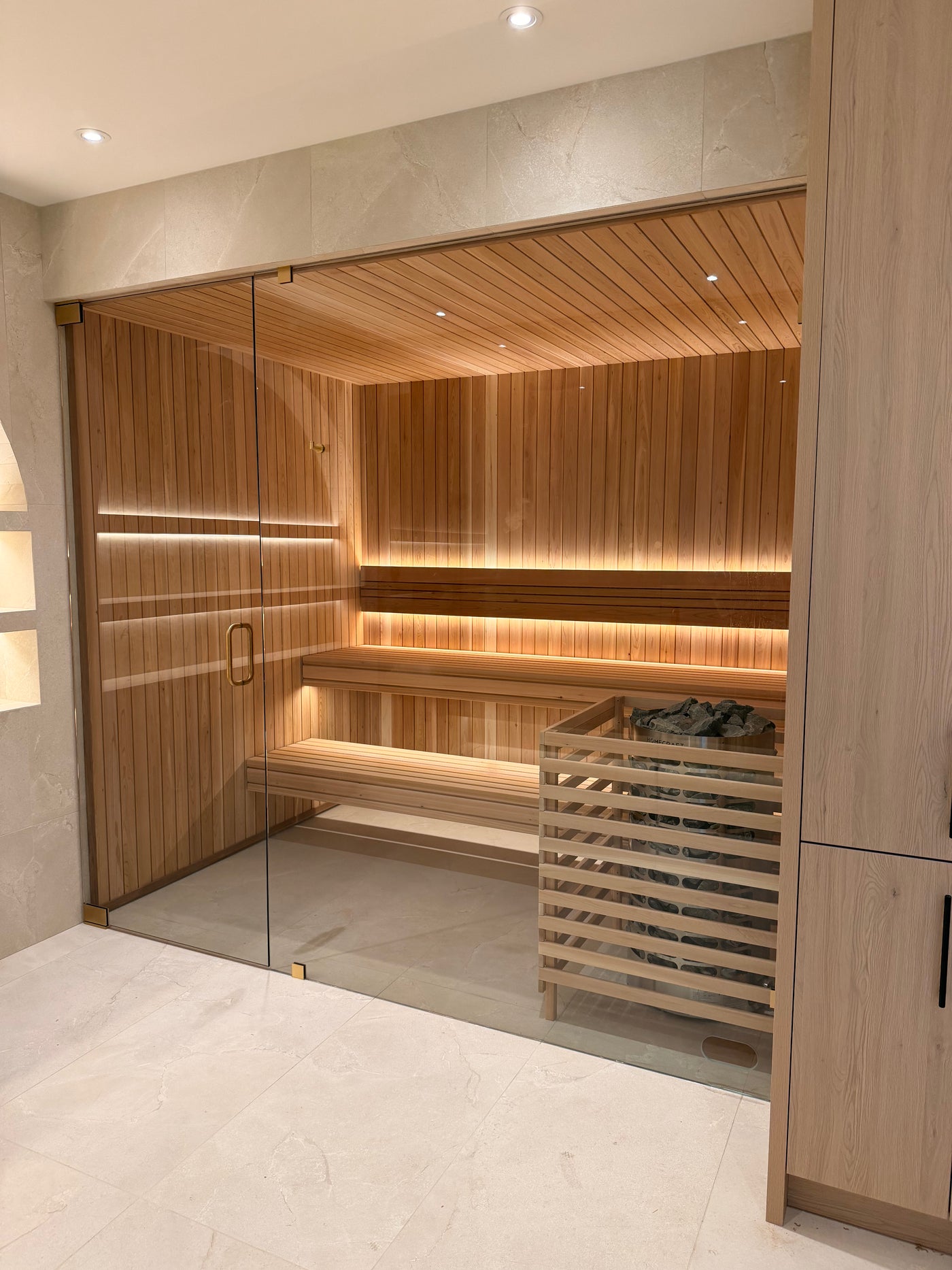 Clear cedar sauna with a glass front and a lit floating backrest, built by Inland